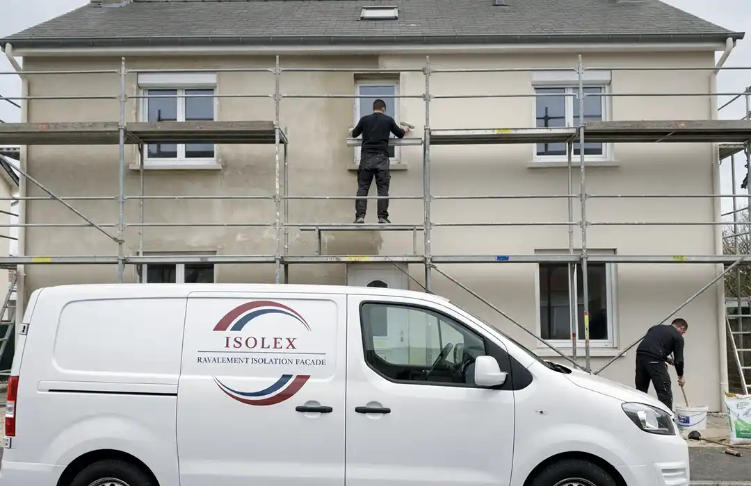 Deux ouvriers r&eacute;novent l'ext&eacute;rieur d'une maison &agrave; l'aide d'un &eacute;chafaudage. L'un se tient sur l'&eacute;chafaudage, peignant pr&egrave;s d'une fen&ecirc;tre, tandis que l'autre travaille au niveau du sol &agrave; c&ocirc;t&eacute; d'une camionnette de l'entreprise Isolex.